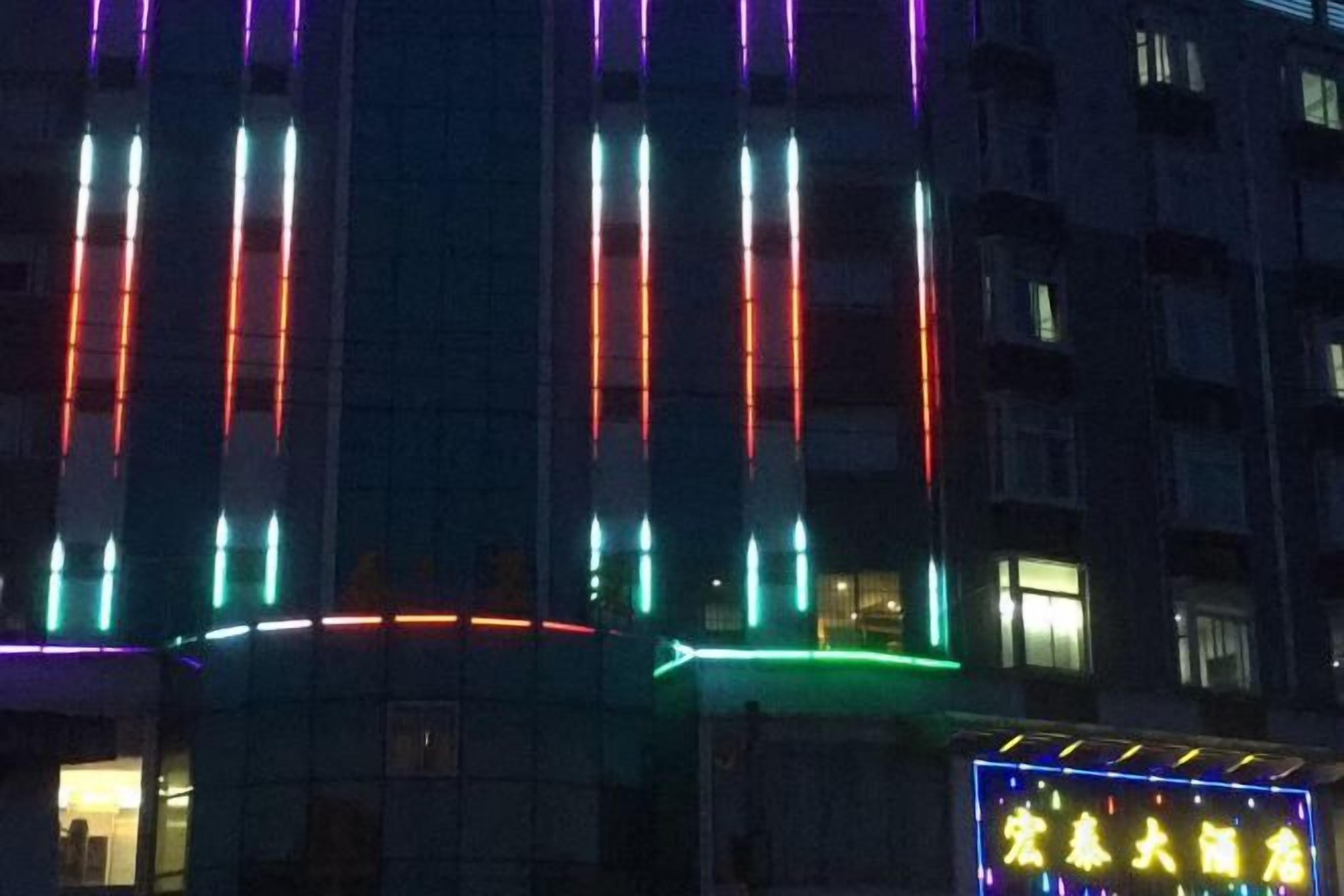 A building facade with vertical light strips and a neon sign.