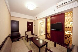 A hotel room with a sofa, a TV mounted on the wall, a wooden coffee table, and a decorative partition. - Pingnan Xiangyue Hotel (Pingnan)