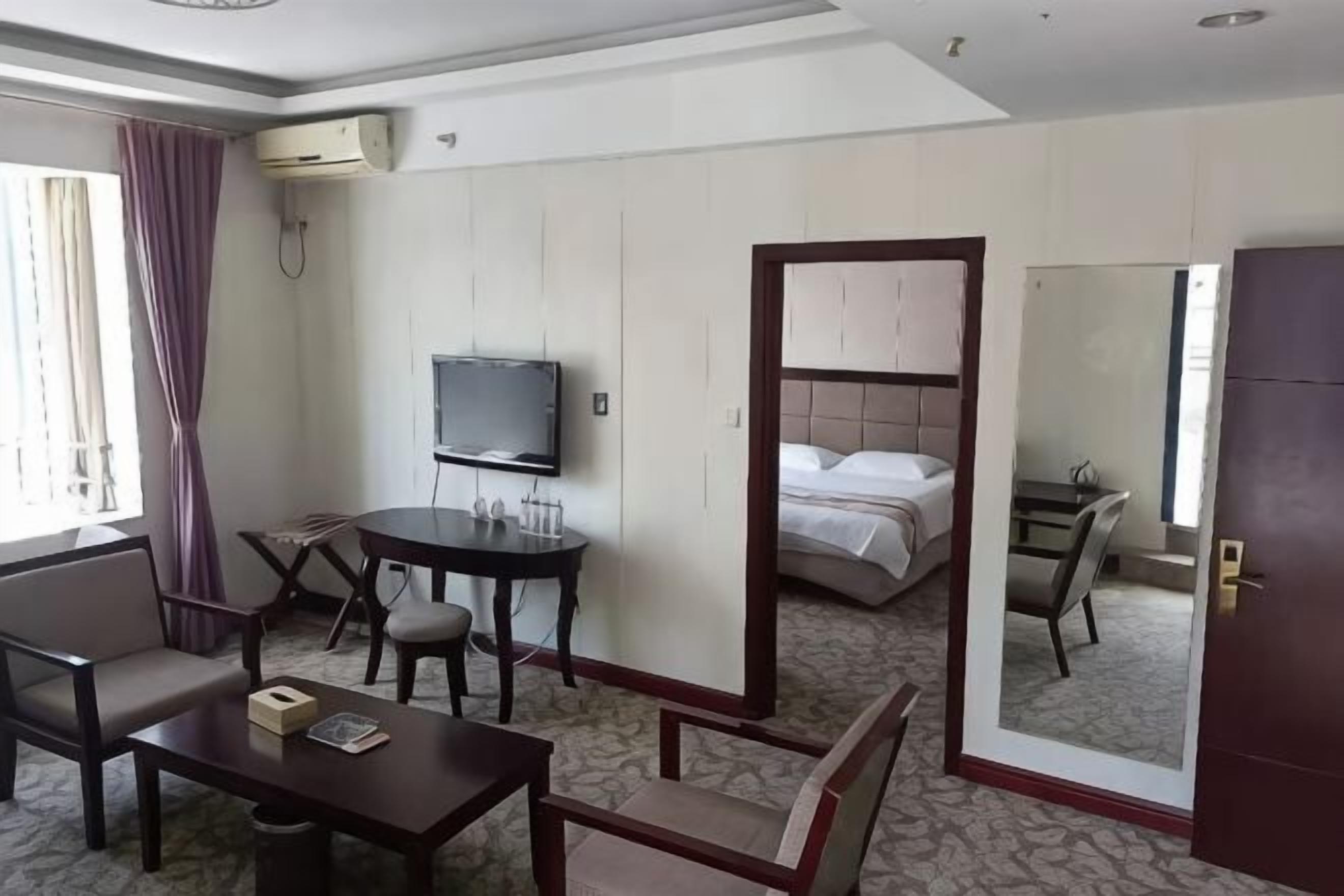 A hotel room with a bed, a TV, a desk, and a mirror.