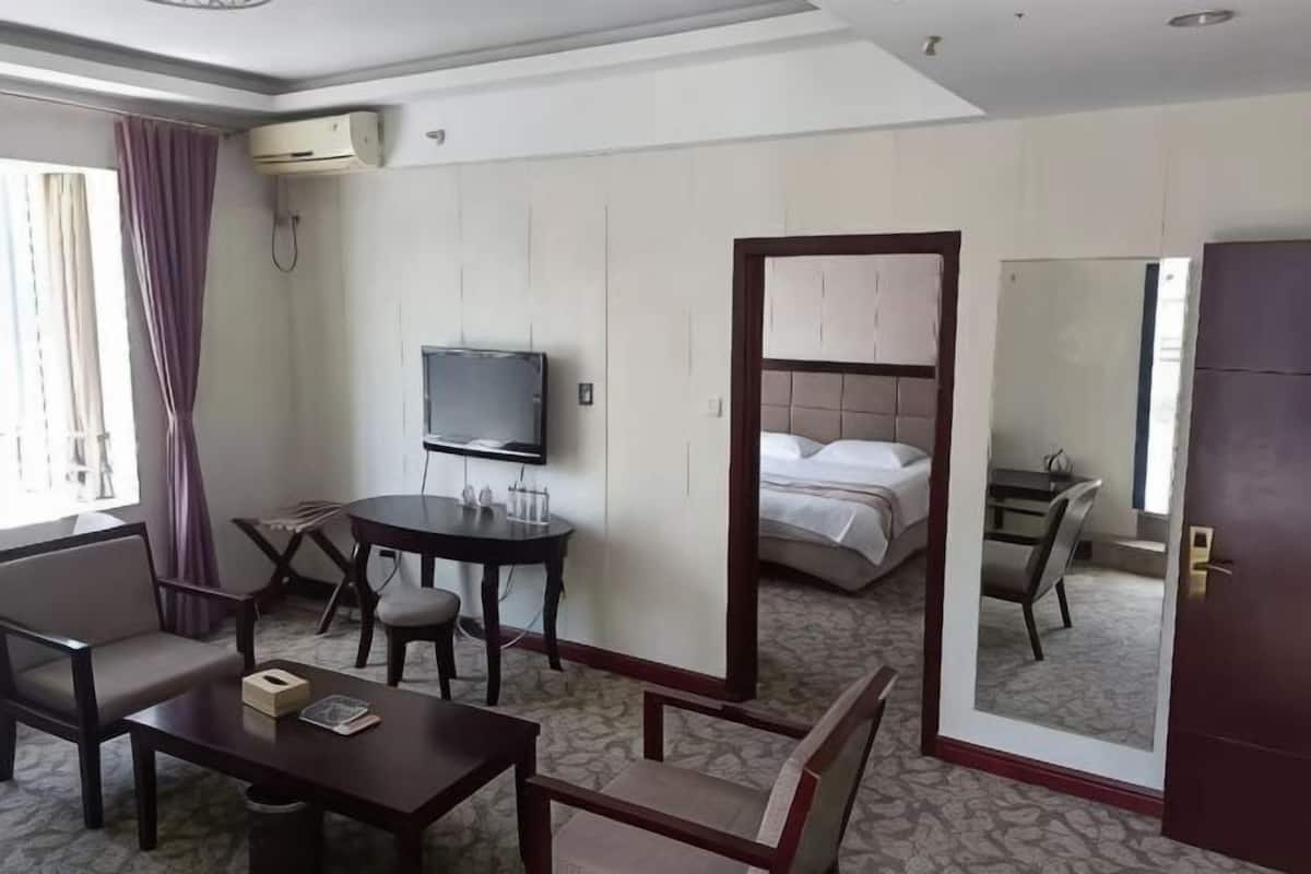 A hotel room with a bed, a TV, a desk, and a mirror.
