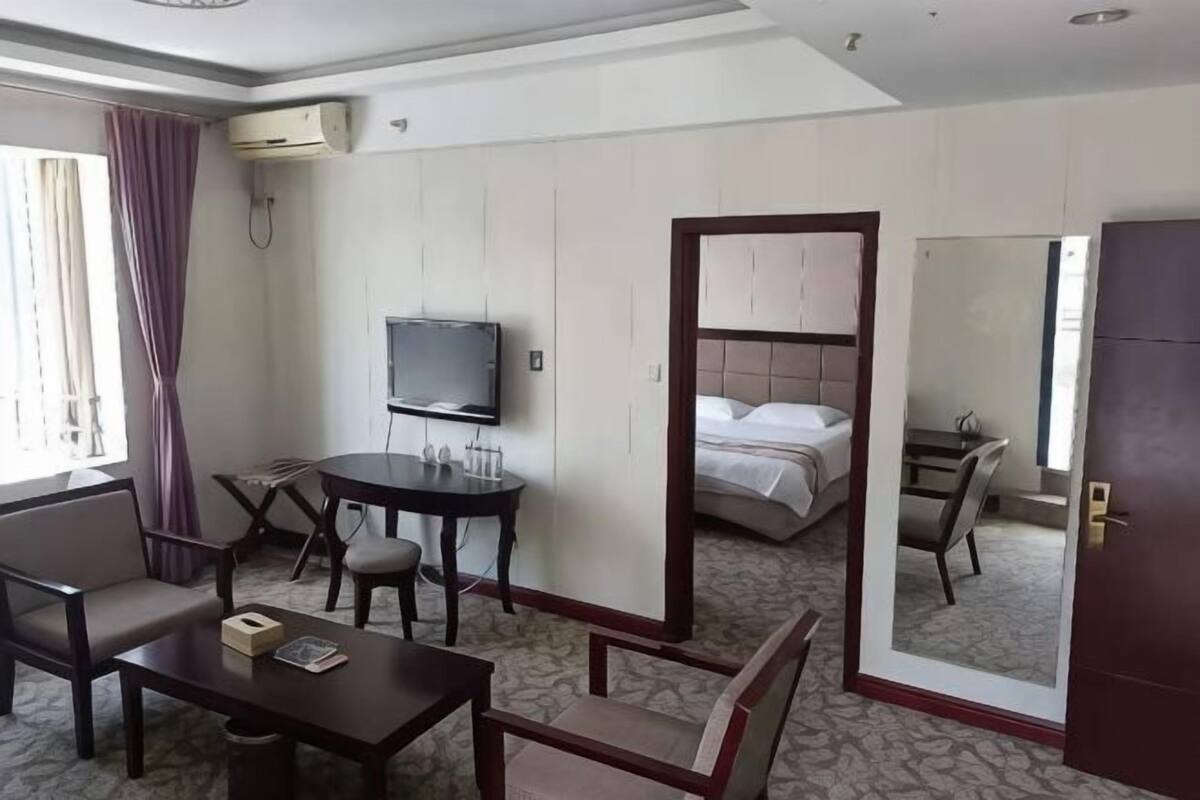 A hotel room with a bed, a TV, a desk, and a mirror.