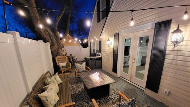 An outdoor patio with a wooden deck, a fire pit, wicker furniture, and string lights. - FR - Heber Historic Colonial (Heber City)