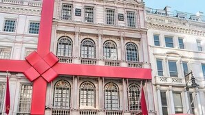 A historic building with a prominent red bow decoration, storefronts labeled 'Cartier', and a classic red telephone booth. - Cosy & Bright Serviced Apartment in Mayfair,London (Greater London)