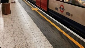 A subway station with a train, tiled floor, and overhead signage. - Cosy & Bright Serviced Apartment in Mayfair,London (Greater London)