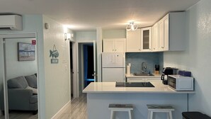 Una cocina moderna con armarios blancos, una isla central con taburetes, microondas integrado y un fregadero.