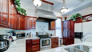 A kitchen with wooden cabinets, stainless steel appliances, a granite countertop, and pendant lighting. - Spacious 7-bedroom, 4 bathroom house with WiFi and new HVAC in wonderful Wichita (Wichita)