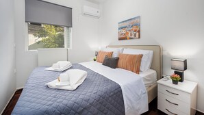 Habitación de hotel con cama, mesita de noche, ventana con vistas y aire acondicionado.