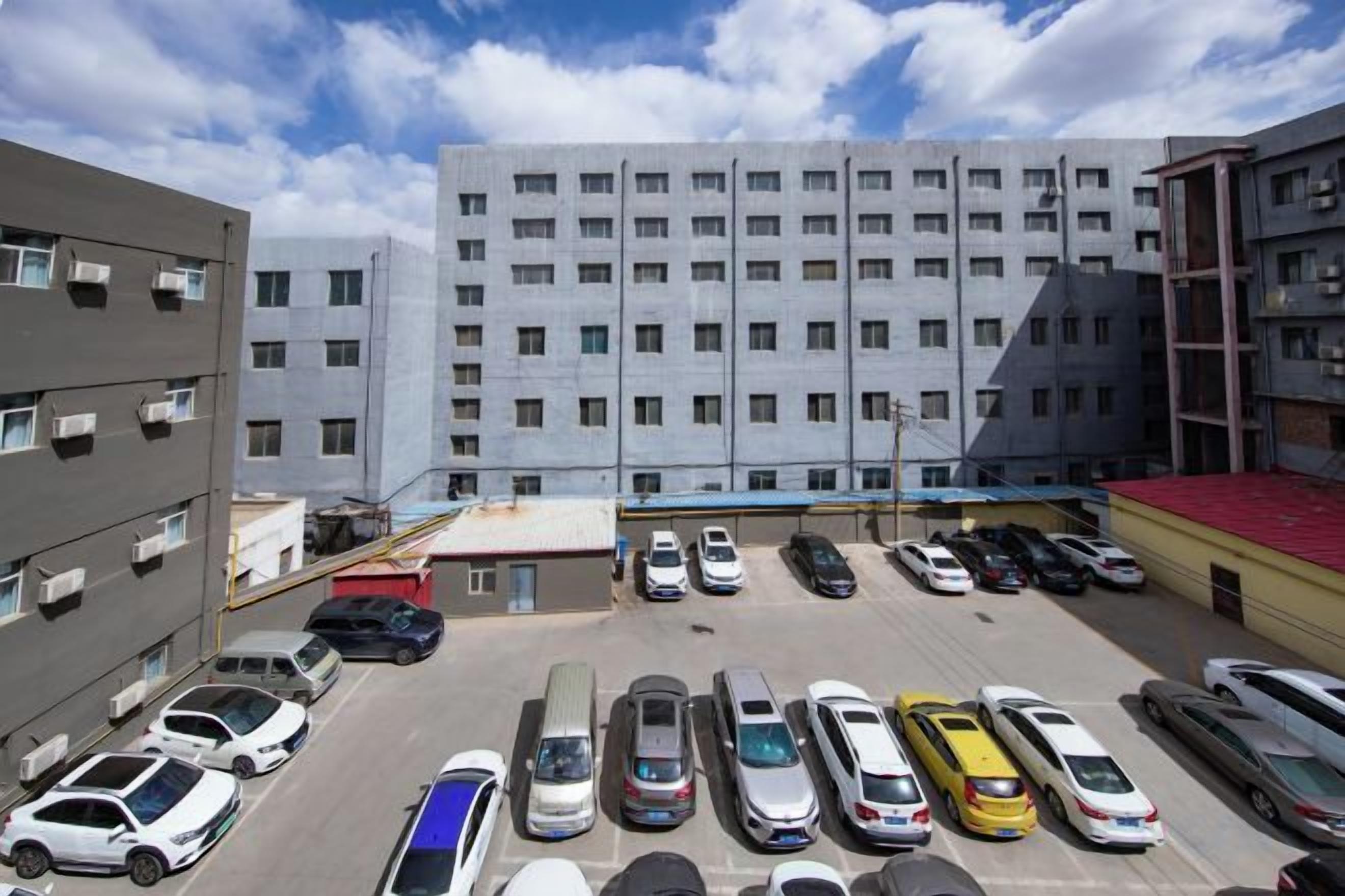 Een parkeerplaats met meerdere auto's en een groot gebouw op de achtergrond.