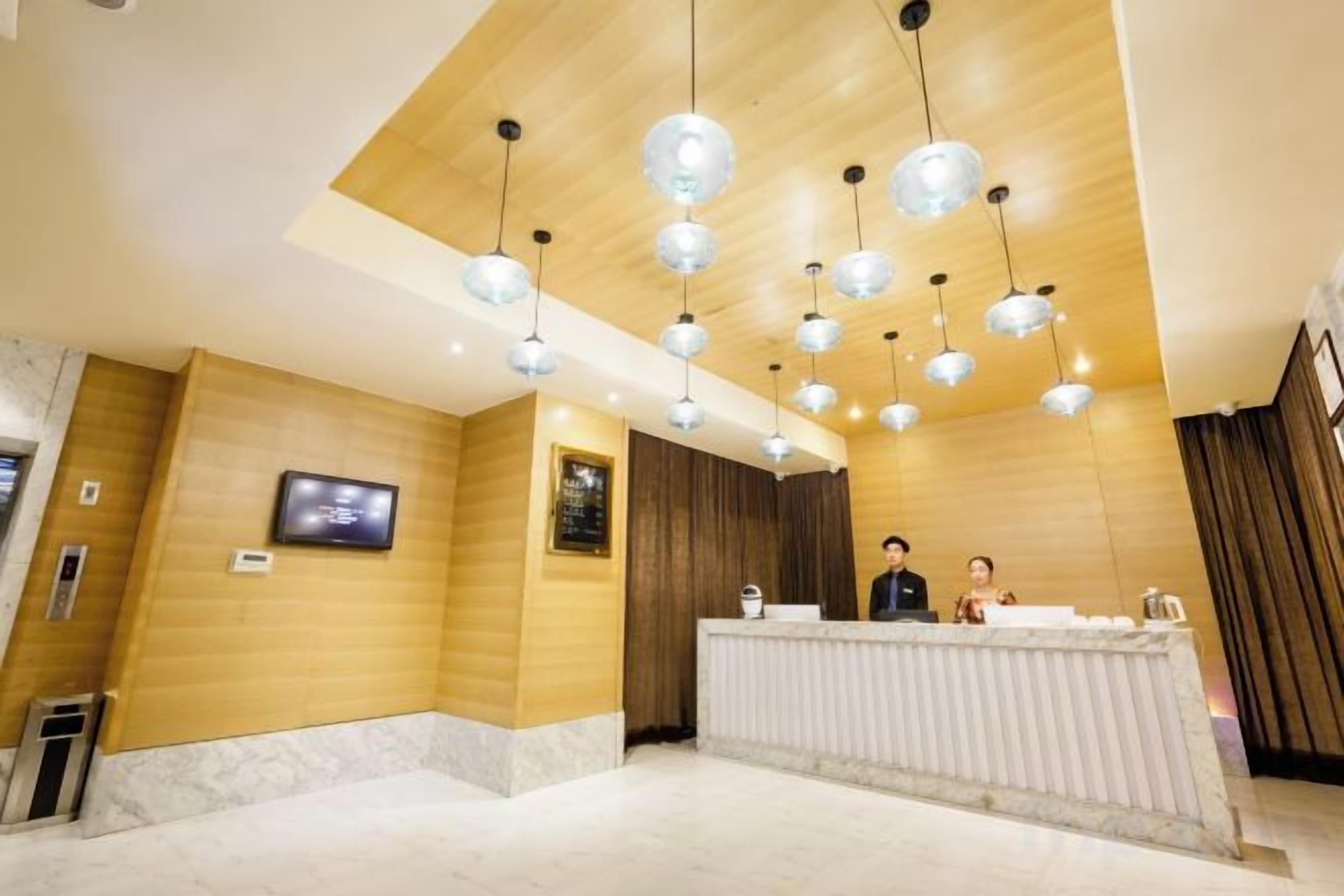 A hotel reception area with a wooden interior, a reception desk, and multiple hanging pendant lights.