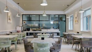 A modern dining area with tables and chairs, pendant lighting, and large windows. - JIN YOTEL(South Second Ring & South Shiyangqiao Road, Hohhot) (Hohhot)