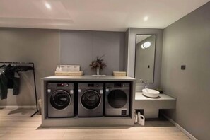 A modern bathroom with a built-in washer and dryer unit, a sink, and a mirror. - JIN YOTEL(South Second Ring & South Shiyangqiao Road, Hohhot) (Hohhot)