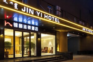 A hotel entrance with a sign that reads 'JIN YI HOTEL' and another sign in a different language.