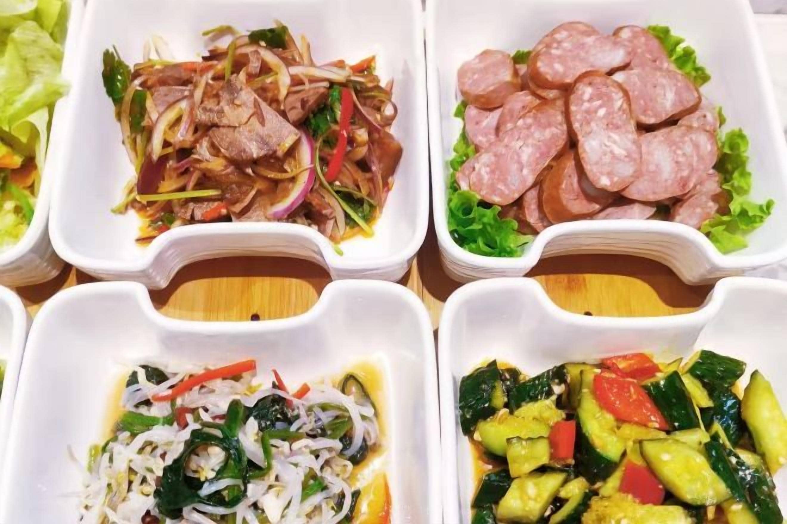 Four white rectangular food containers with different dishes.