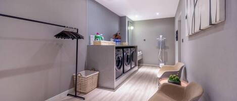 A laundry room with a washing machine, dryer, and a drying rack.