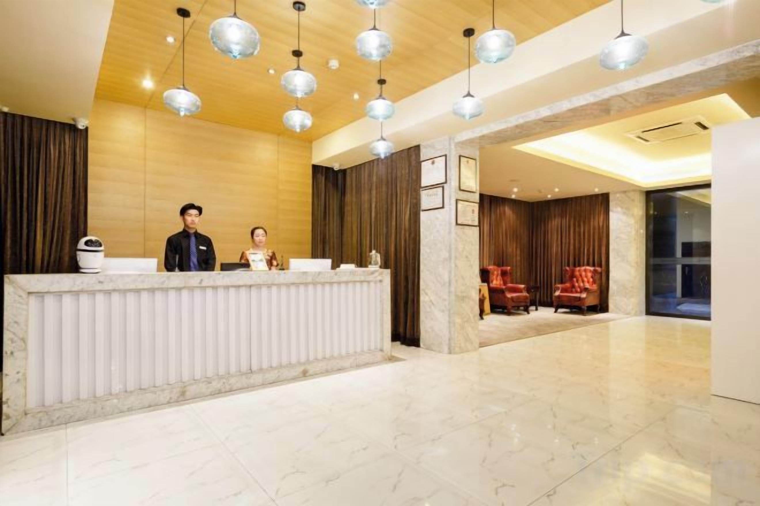 A hotel reception area with a marble reception desk, two receptionists, and a modern interior design.