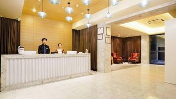 A hotel reception area with a marble reception desk, two receptionists, and a modern interior design.
