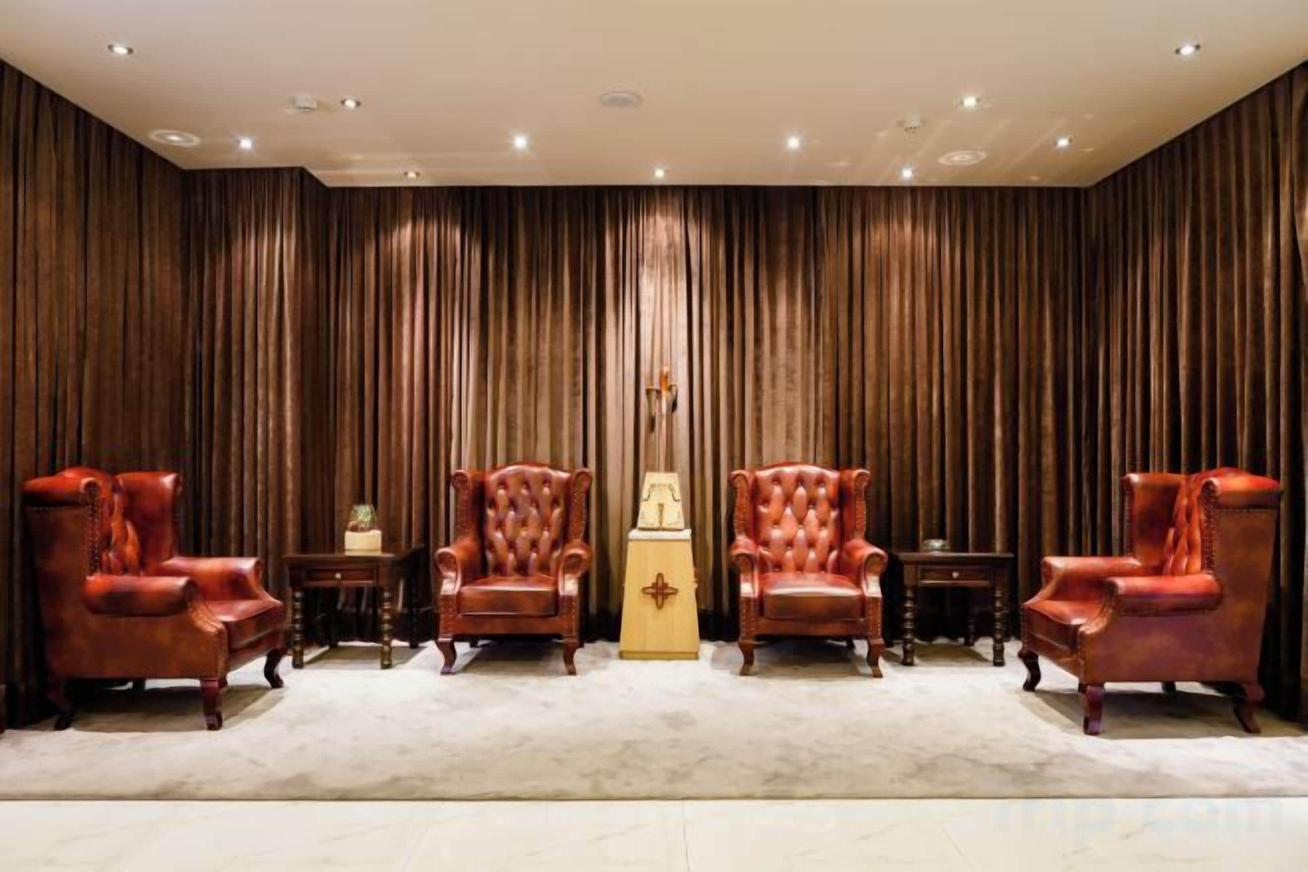 A room with four leather armchairs, a small table, and a decorative item in the center.