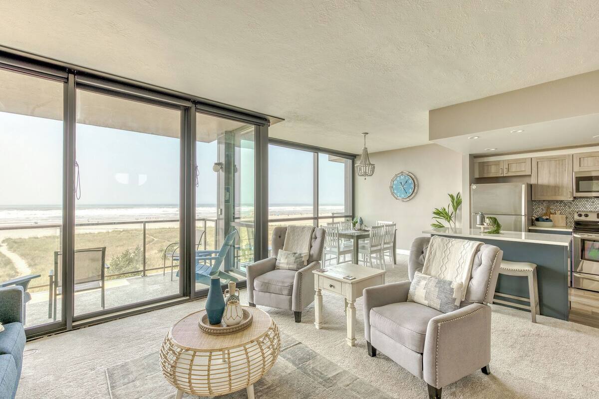 Un ampio balcone con vista sulla spiaggia, arredato con sedie e un tavolo, e un angolo cottura dotato di elettrodomestici moderni.