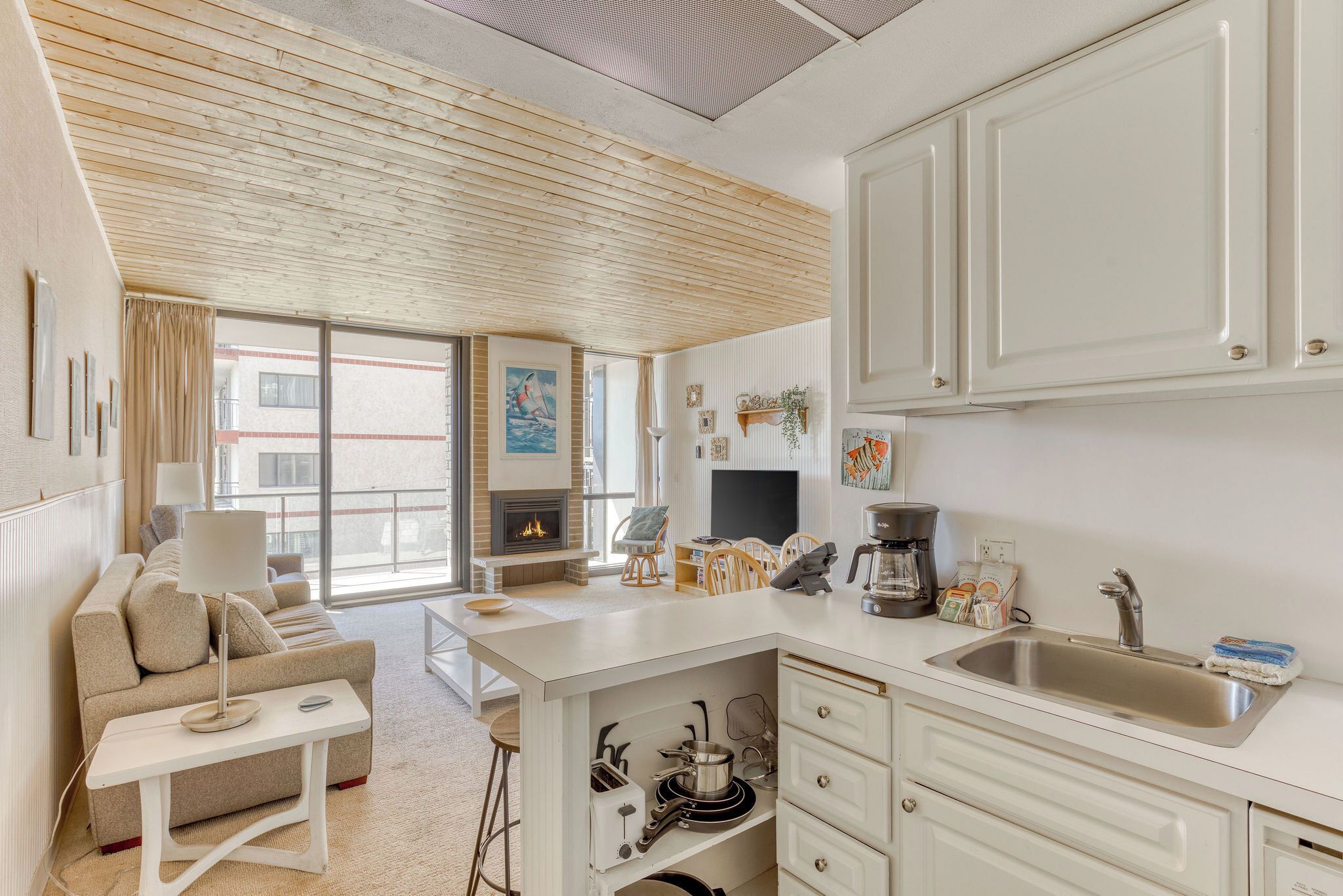 Una cocina moderna con armarios blancos, una isla integrada y un ventanal grande.
