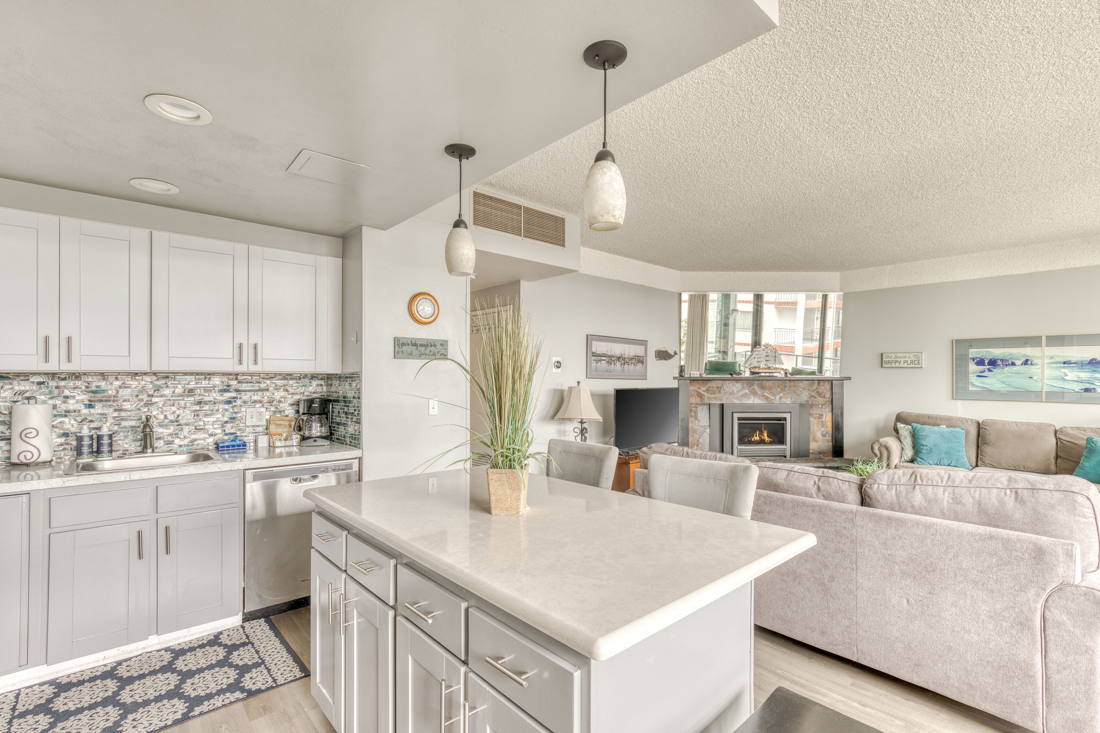 A modern kitchen with white cabinets, a central island, and pendant lighting.