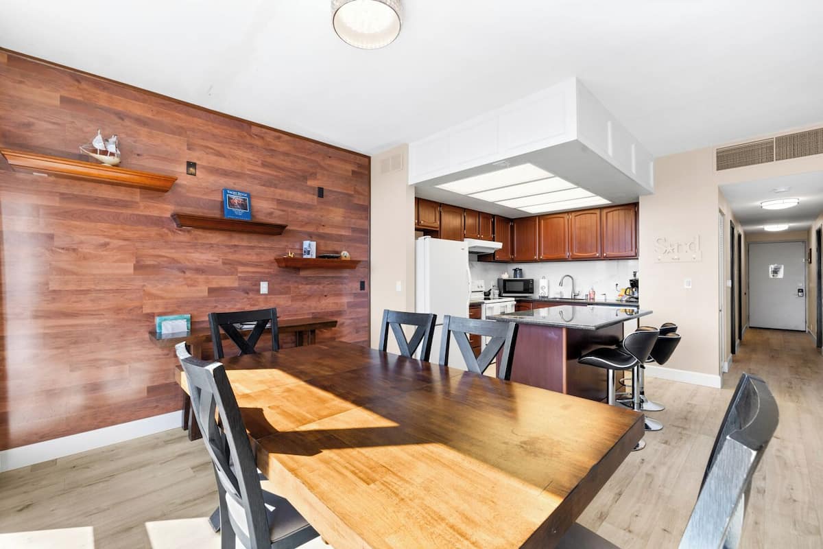 Una cucina moderna con mobili in legno, un'isola centrale e un'area pranzo con tavolo e sedie in legno.