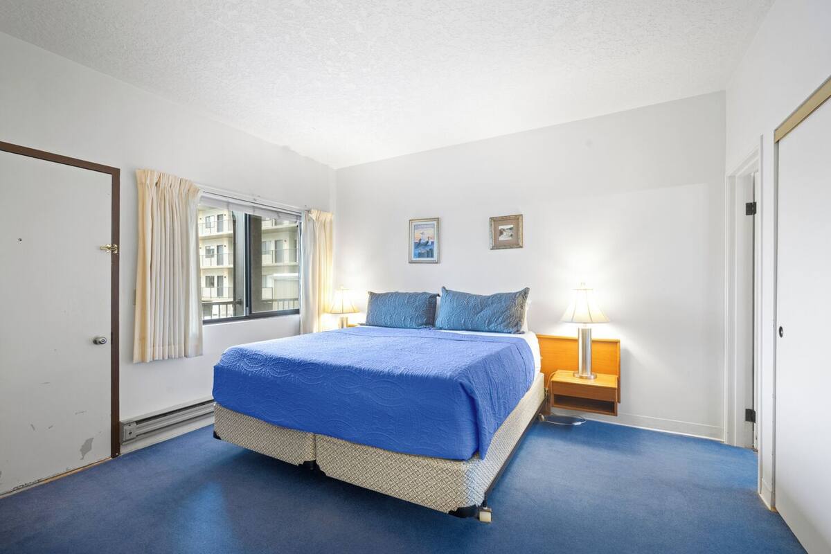 Una camera da letto con un letto, una finestra, un comodino e una lampada.