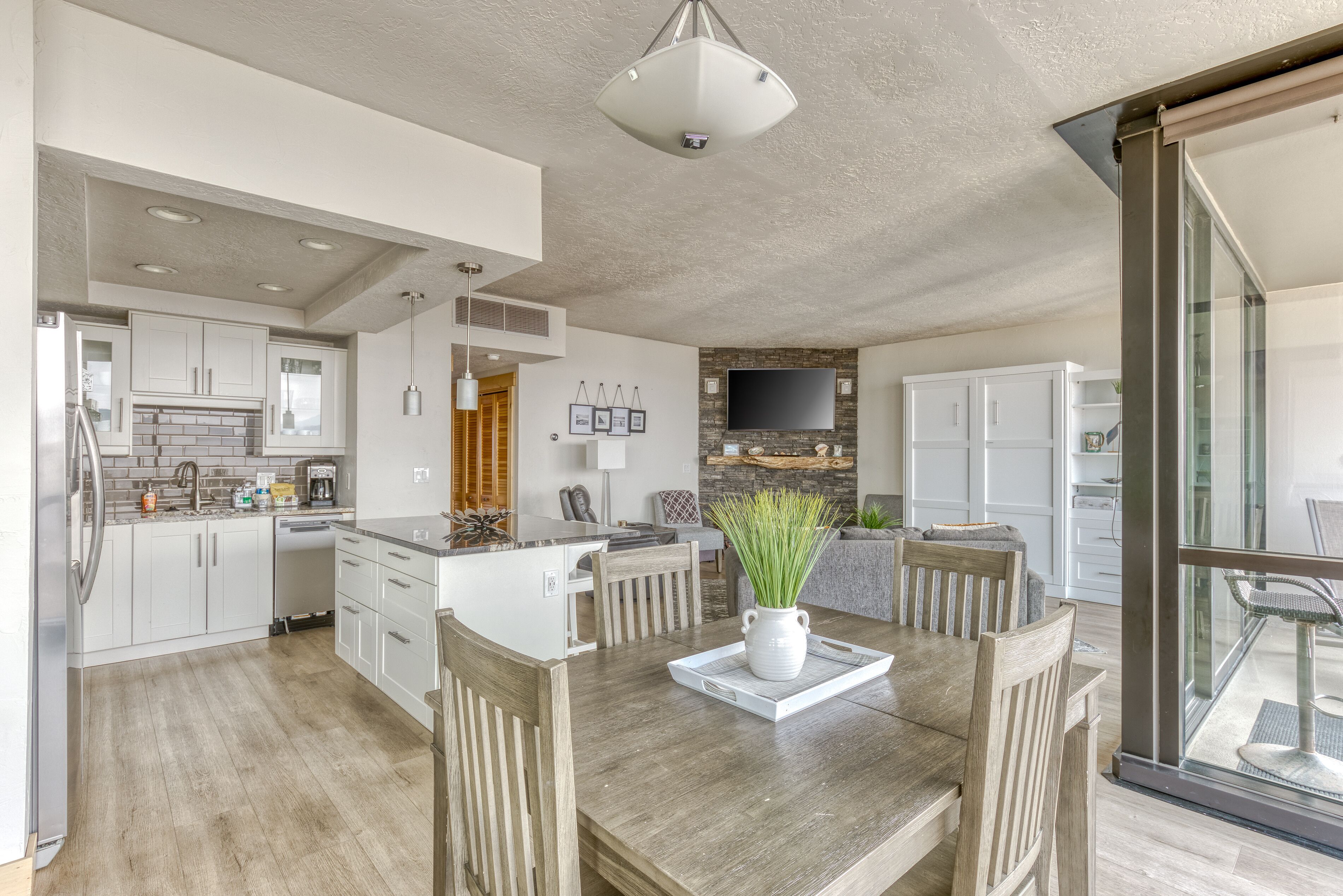 Een moderne keuken met witte kasten, een inbouwoven en een eethoek met een houten tafel en stoelen.