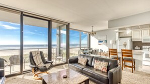 Un vaste espace de vie avec une grande porte-fenêtre coulissante donnant sur un balcon avec vue sur la plage.