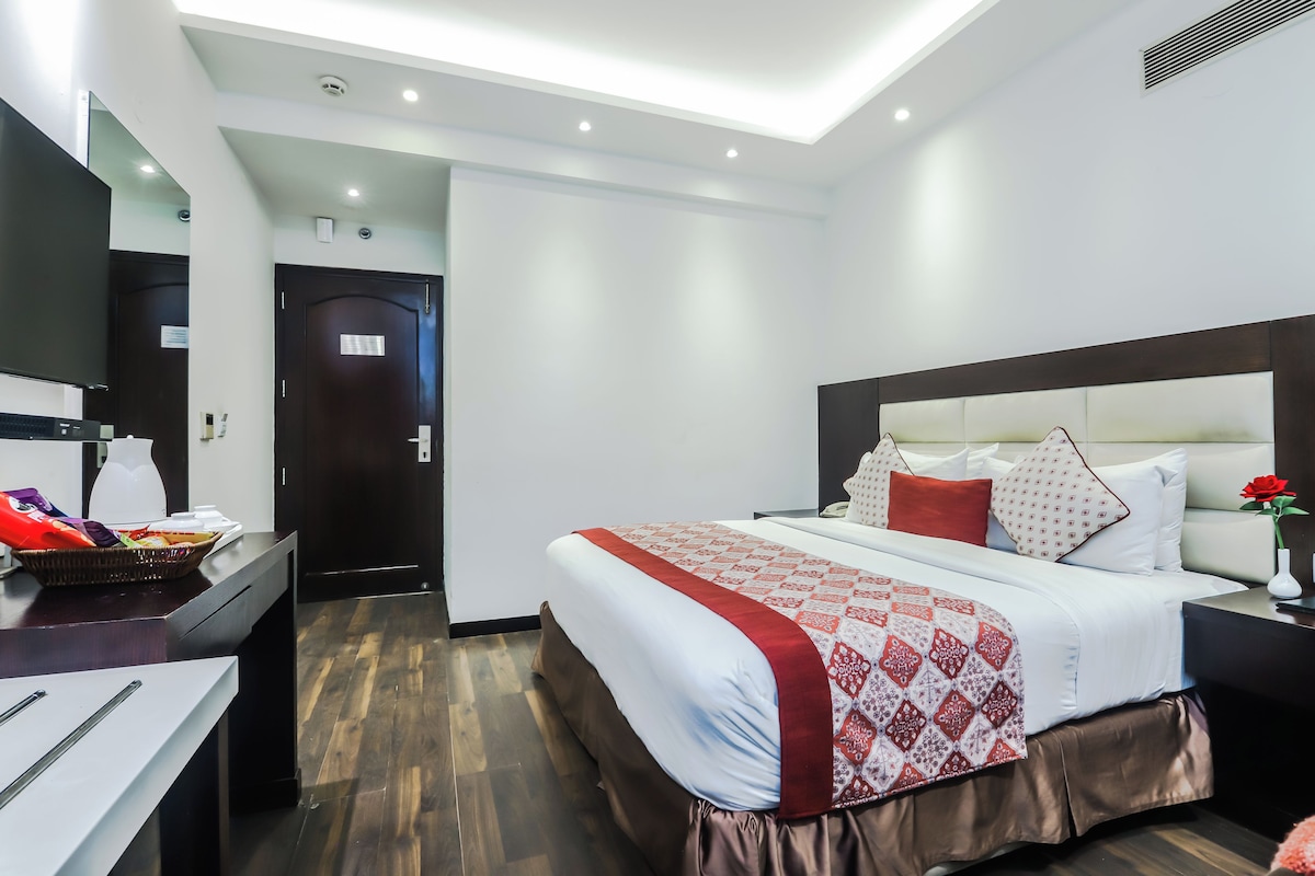 Ein Hotelzimmer mit Bett, Nachttisch und Schreibtisch mit einer Korb voller Snacks.