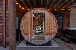 A wooden sauna with a glass door, a bench outside, and a wooden exterior.