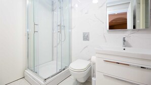 A modern bathroom with a glass-enclosed shower, a white toilet, and a vanity with a mirror. - Karma Suites by Dominium Studio ground floor (Dubrovnik)