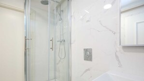A modern bathroom with a glass-enclosed shower, a white sink, and marble-patterned walls. - Karma Suites by Dominium Studio ground floor (Dubrovnik)