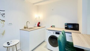 A compact kitchen with a sink, a microwave, and a washing machine. - Karma Suites by Dominium Studio ground floor (Dubrovnik)