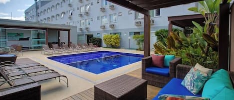 A pool area with lounge chairs and a covered seating area.