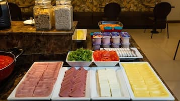 Buffet-pöydässä on tarjolla monenlaista ruokaa, kuten viipaloituja lihatuotteita, juustoja ja kasviksia.