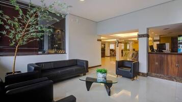 A modern lobby with a black leather sofa, a glass coffee table, and a reception desk.