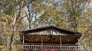 Una baita di legno con un balcone, immersa tra gli alberi.