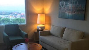 A living room with a sofa, a chair, a small table, a lamp, and a painting on the wall. - Khas Surabaya Hotel (Pabean Cantikan)