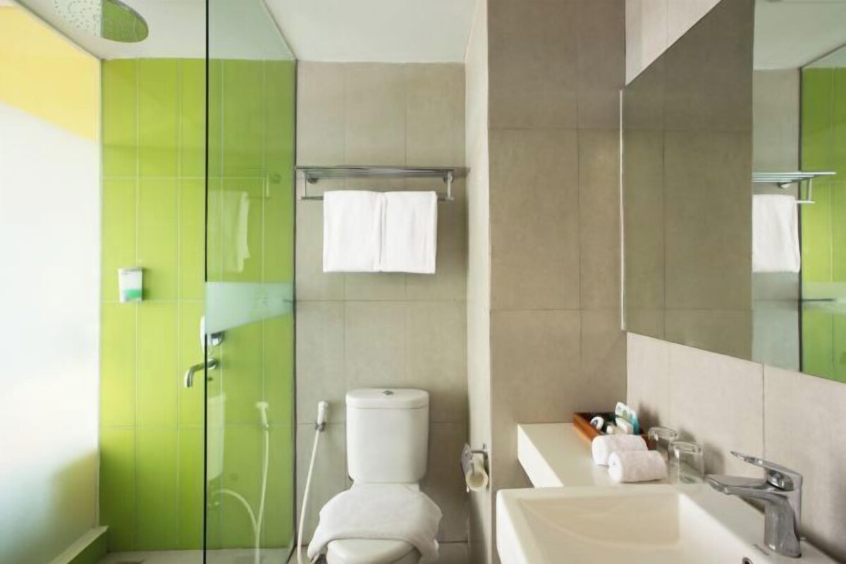 Un baño moderno con cabina de ducha de vidrio, inodoro, lavabo con espejo y perchero para toallas.