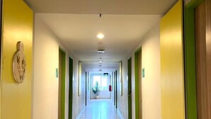 A long, well-lit hallway with doors on both sides, leading to rooms. - Khas Surabaya Hotel (Pabean Cantikan)