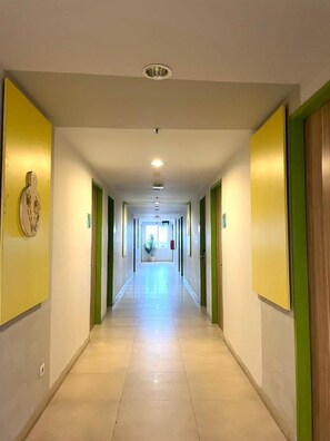 A long, well-lit hallway with doors on both sides, leading to rooms.