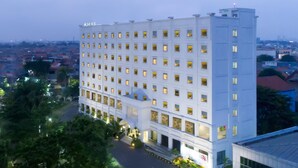 A multi-story hotel with a uniform facade, numerous windows, and a central entrance with steps. - Khas Surabaya Hotel (Pabean Cantikan)