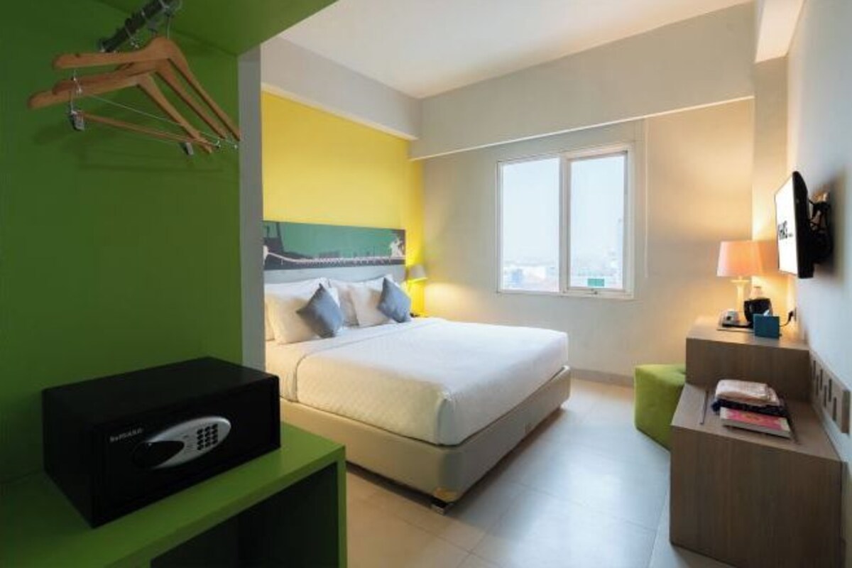 Une chambre d’hôtel moderne équipée d’un lit, d’un bureau, d’une chaise, d’une télévision et d’une fenêtre.
