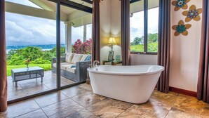 Un baño con bañera, cabina de ducha con mampara de vidrio y vistas al exterior.