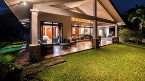 Una casa moderna con un porche cubierto, un interior bien iluminado y un césped cuidado.