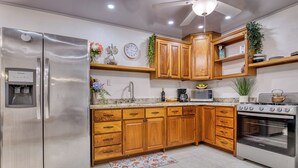 A modern kitchen with wooden cabinets, stainless steel appliances, a built-in oven, and a water dispenser.