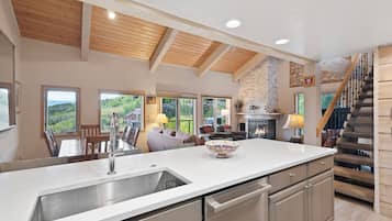 A spacious kitchen with a large island, wooden ceiling beams, and a fireplace.