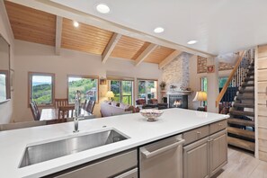 A spacious kitchen with a large island, wooden ceiling beams, and a fireplace. - Snowmass Mountain by Snowmass Vacations (Snowmass Village)