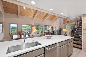 Una cocina amplia con una isla grande, vigas de madera en el techo y una chimenea.