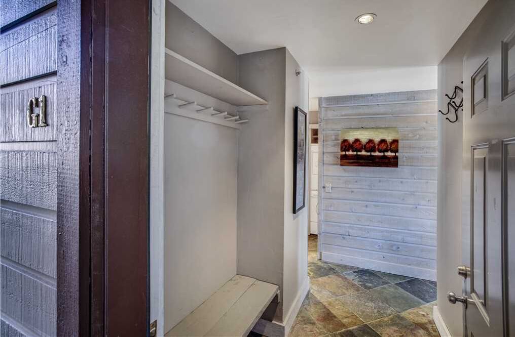 A hallway with a wooden door, a white shelf, and a painting on the wall.